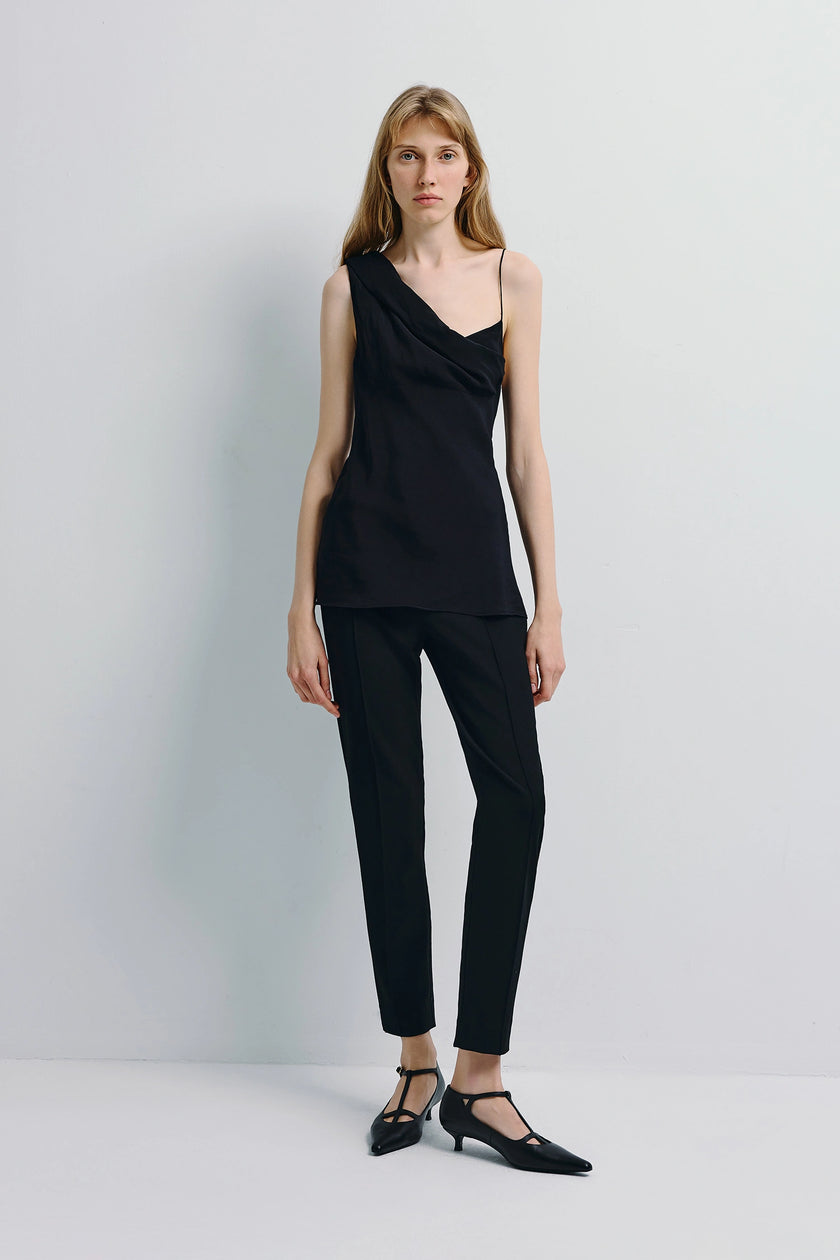 Manuela Asymmetric Cami Top in black, featuring an asymmetrical neckline and paired with black trousers