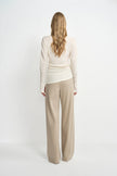 A model wearing oatmeal wide-leg wool-blend trousers, back view showing the relaxed silhouette and fluid drape, pairing an ivory draped top.