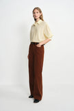 A model wearing a brown corduroy pant with a relaxed straight leg, side view.