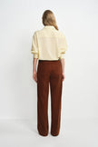 A model wearing a brown corduroy pant, back view, showing a relaxed straight leg silhouette.