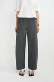 A model wearing dark gray wide-leg wool trousers, styled with a white short-sleeve top and black-and-white sandals against a plain white studio background.