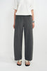 A model wearing dark gray wide-leg wool trousers, styled with a white short-sleeve top and black-and-white sandals against a plain white studio background.