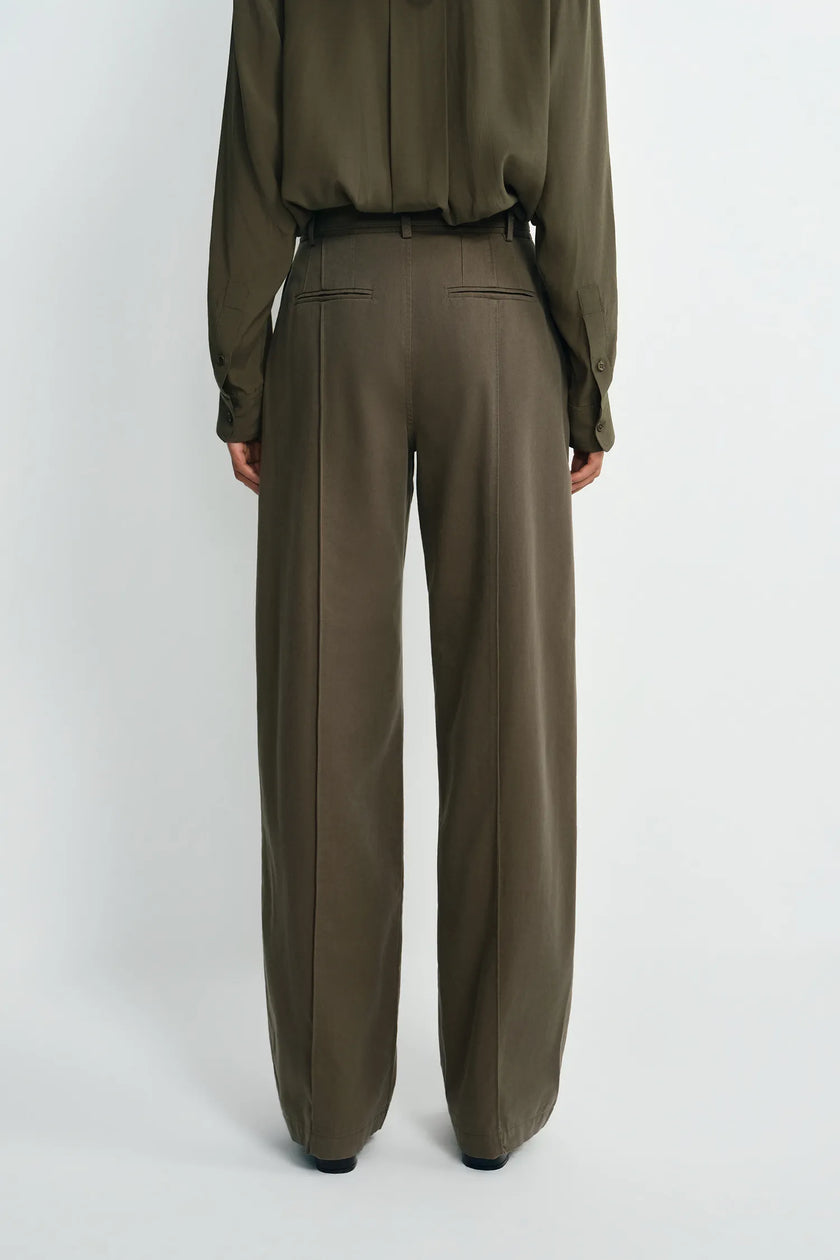 A model shown from the back wearing a matching olive green long-sleeve blouse and wide-leg trousers, photographed against a plain light gray studio background.