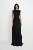 A model wearing a sleeveless black maxi dress with a textured knit bodice and a flowing chiffon skirt, standing against a plain light gray studio background.