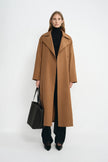 A model wearing a coppery brown oversized trench coat, open front, pairing dark wash jeans.