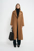 A model wearing a coppery brown oversized trench coat, open front, pairing dark wash jeans.