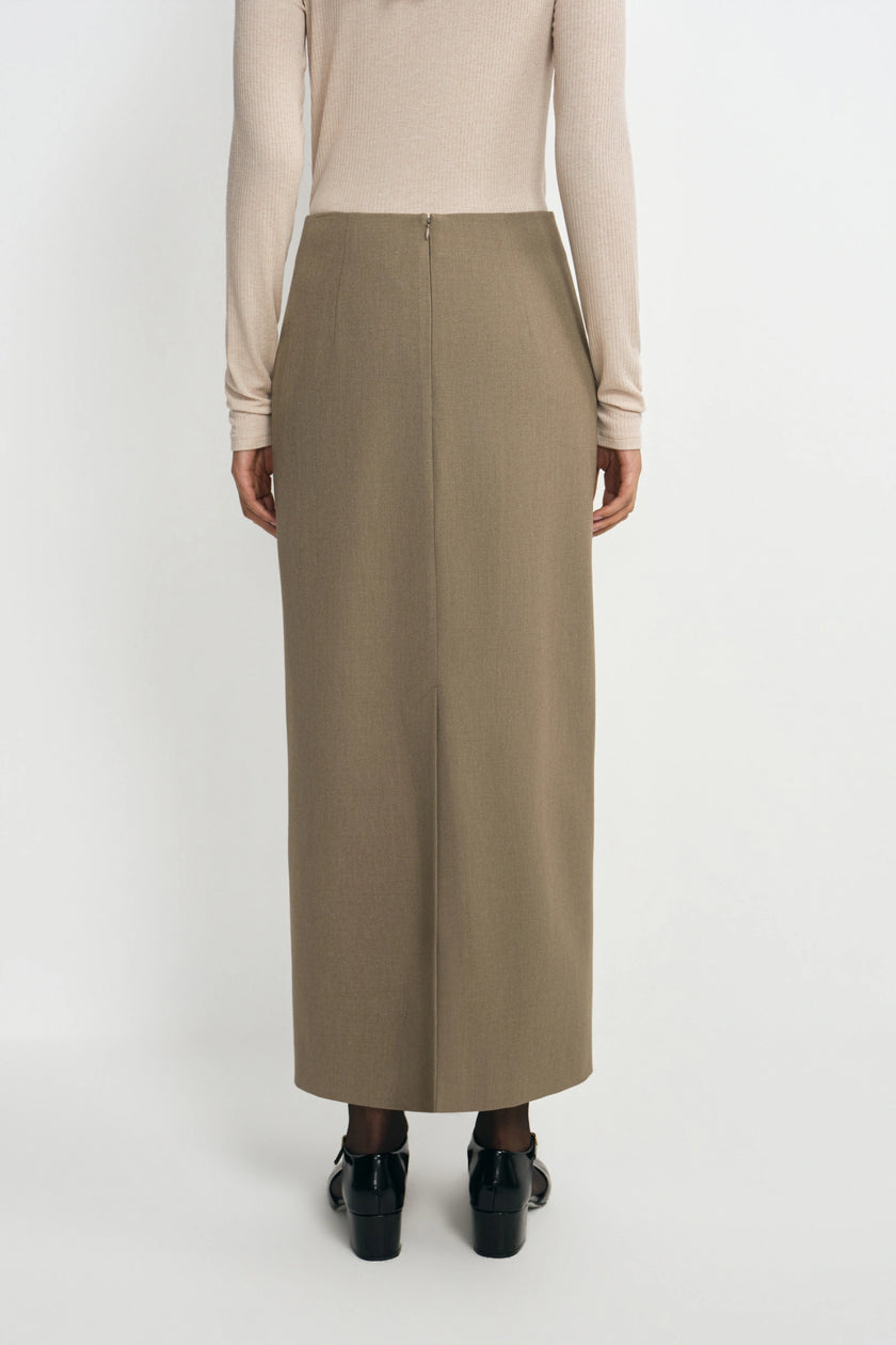 A model wearing an oatmeal pencil midi skirt, back view showing the back zip closure and center back hem slit, pairing a beige turtleneck top and black Mary Jane heels.