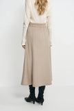 Rear three-quarter view of an oatmeal wool midi skirt on a model, showing the gathered waistband above a flared hem and black heeled boots.