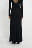 A model wearing a black fluid viscose maxi skirt, back view, showing the A-line sweep.