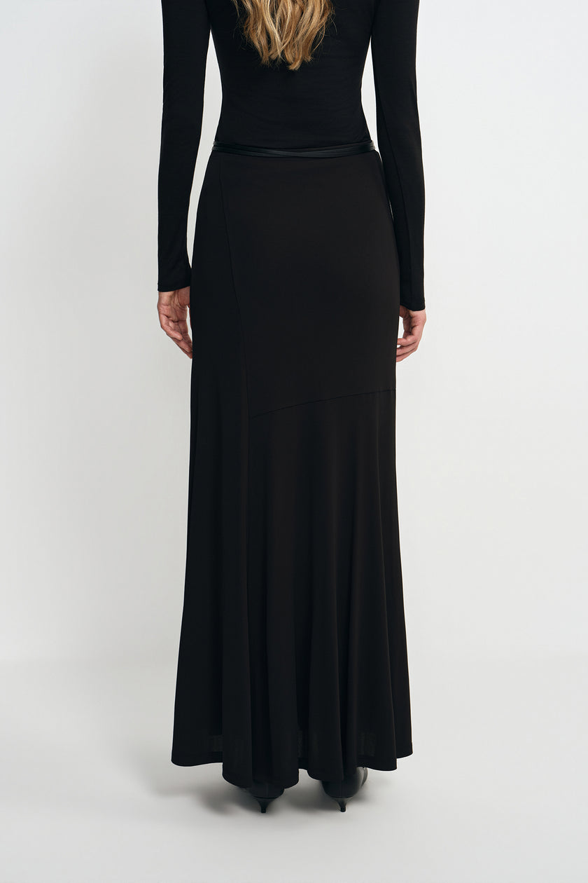A model wearing a black fluid viscose maxi skirt, back view, showing the A-line sweep.