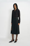 A model wearing a charcoal A-line skirt, pairing a plaid button-up shirt with a belted waist.