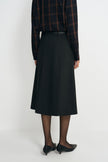 A model wearing a charcoal A-line skirt with a vented back pleat, pairing a plaid button-up shirt, back view.