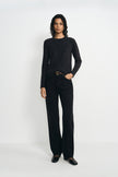 A model wearing a charcoal wool crewneck sweater, pairing black wide-leg jeans with a belt.