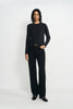 A model wearing a charcoal wool crewneck sweater, pairing black wide-leg jeans with a belt.