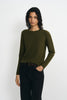 A model wearing an olive green long-sleeve knit sweater and black jeans, standing against a plain white studio background.