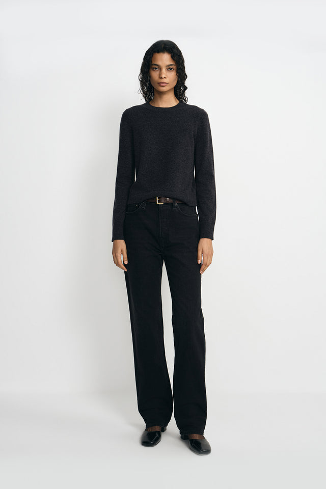 A model wearing a charcoal wool crewneck sweater, pairing black wide-leg jeans.