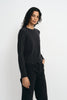 A model wearing a charcoal wool crewneck sweater, pairing black wide-leg jeans, side view.