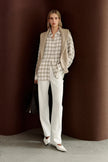 A model wearing Rue Sophie’s Elouet Plaid Oversized Shirt in Ivory Plaid, showing its relaxed button-down silhouette and soft neutral check pattern.