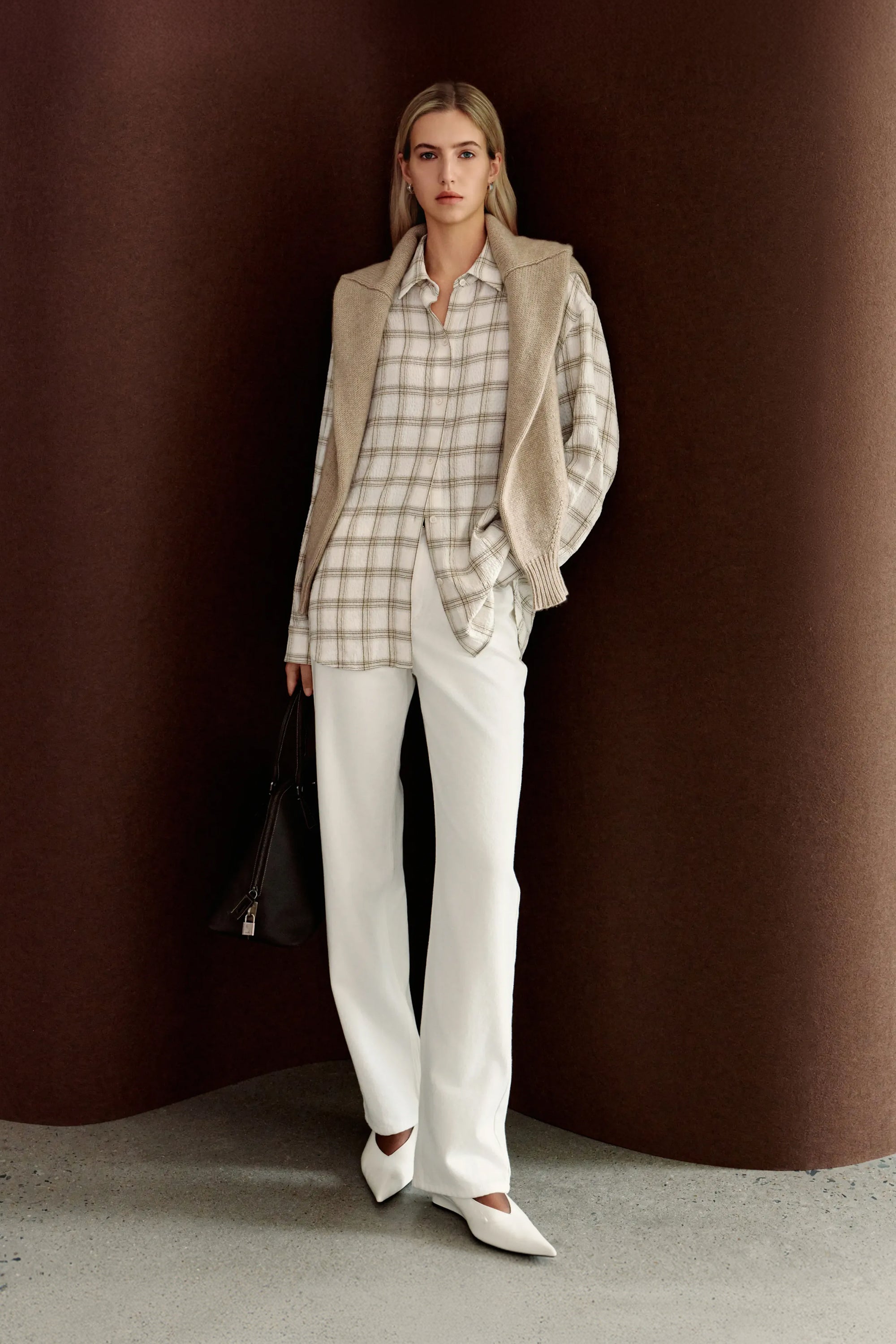 A model wearing Rue Sophie’s Elouet Plaid Oversized Shirt in Ivory Plaid, showing its relaxed button-down silhouette and soft neutral check pattern.