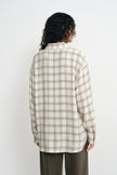 A model wearing a fluid plaid shirt, pairing forest wide-leg trousers, back view.