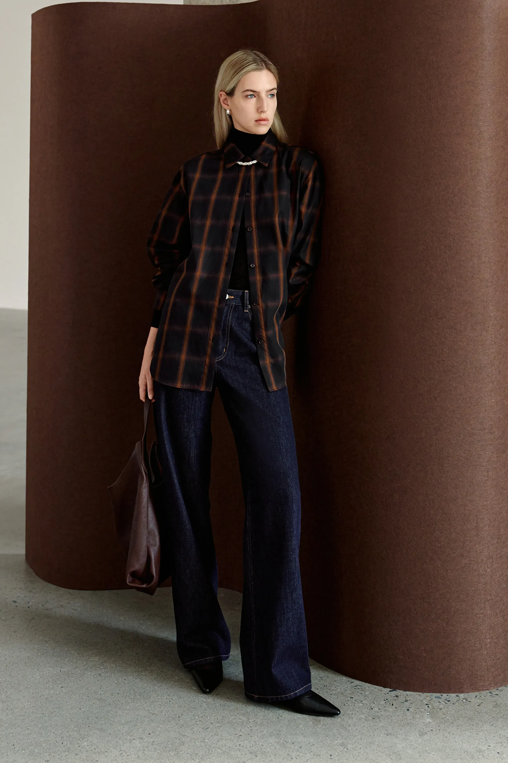 A model wearing Rue Sophie’s Elouet Plaid Oversized Shirt in Navy Plaid, featuring a pointed collar, button front and relaxed longline silhouette.