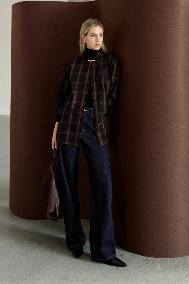 A model wearing Rue Sophie’s Elouet Plaid Oversized Shirt in Navy Plaid, featuring a pointed collar, button front and relaxed longline silhouette.