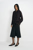 A model wearing a plaid button-up shirt, pairing a charcoal A-line midi skirt, turned slightly to the side.