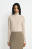 A model wearing a light beige ribbed turtleneck sweater and a taupe pencil skirt, standing against a plain white studio background.