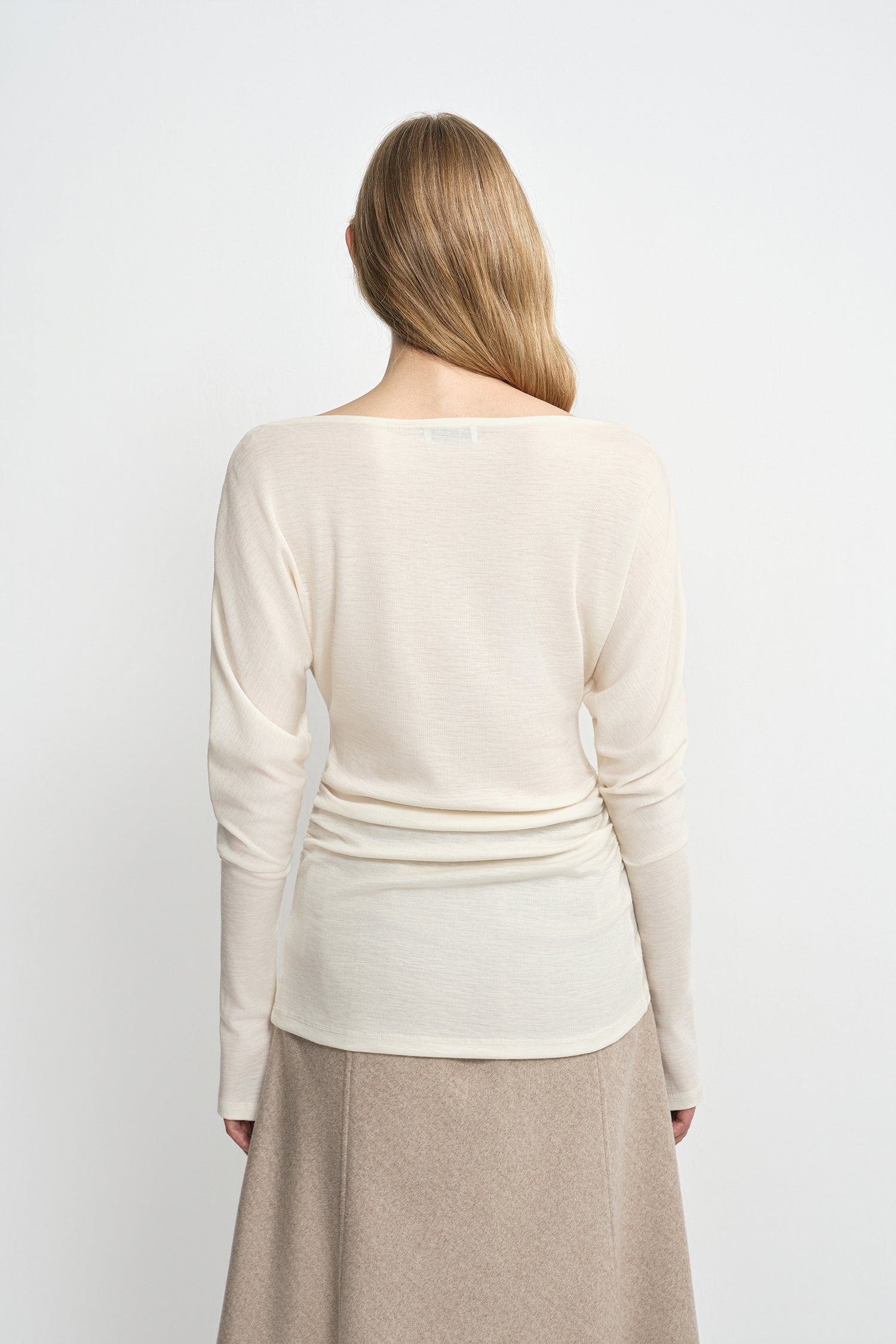 Close-up of an ivory top showing the soft draped fabric across the shoulders and back.