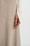 Close-up of a khaki flared midi skirt seam detail, paired with an ivory long sleeve top with a slit cuff.