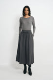 A model facing forward in a medium-grey ribbed top, tucked into a charcoal drawstring midi skirt and paired with black heeled boots.