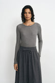 Close-up of a model wearing a medium-grey lyocell-wool top, showing fine ribbing, a narrow crewneck edge and long sleeves above a charcoal skirt.