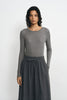 Close-up of a model wearing a medium-grey lyocell-wool top, showing fine ribbing, a narrow crewneck edge and long sleeves above a charcoal skirt.