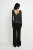 Back view of a model in a charcoal-heather top, showing the deep V-back, long sleeves and gathered waist above dark brown wide-leg trousers.