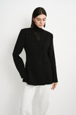 A model wearing the Rue Sophie Marion Side Slit Jacket in black, featuring a deep V-neckline, structured shoulders, welt pockets, and a defined waist, three-quarter front view.