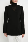 Close-up of the Rue Sophie Marion Side Slit Jacket in black, highlighting the collarless V-neckline, structured shoulders, welt pockets, and tailored waist construction.
