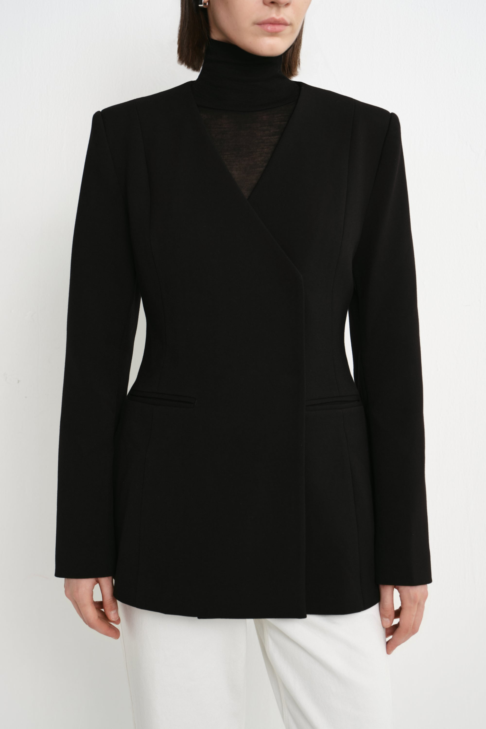 Close-up of the Rue Sophie Marion Side Slit Jacket in black, highlighting the collarless V-neckline, structured shoulders, welt pockets, and tailored waist construction.