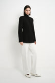 A model wearing the Rue Sophie Marion Side Slit Jacket in black with a collarless V-neckline, long sleeves, structured shoulders, and a tailored waist, three-quarter view.