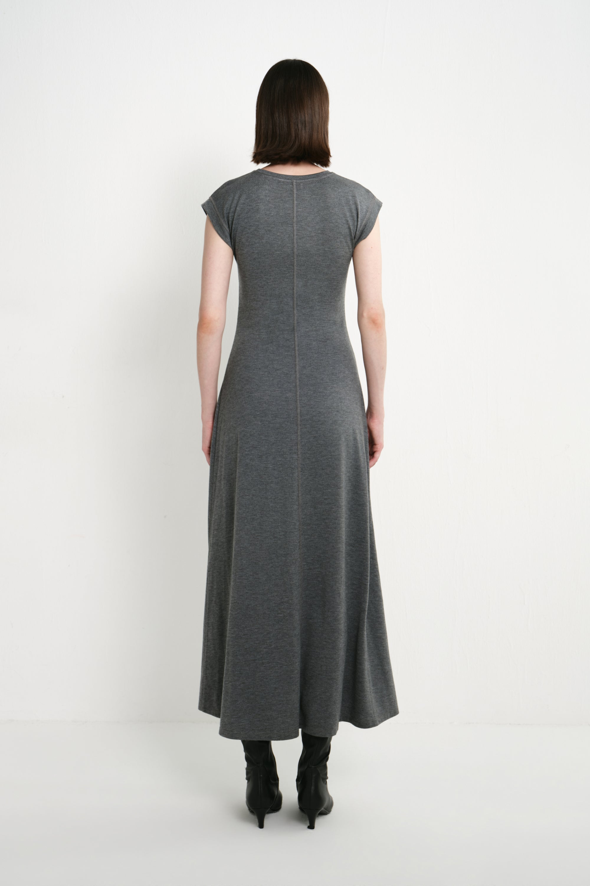 Back view of a model wearing the Rue Sophie Avi Out Stitched Dress in heather charcoal, featuring cap sleeves, center-back stitching, and a flowing A-line silhouette.