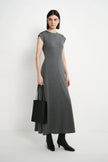 A model wearing the Rue Sophie Avi Out Stitched Dress in heather charcoal with exposed center stitching and a long flared silhouette, three-quarter front view.