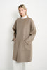 A model wearing a Rue Sophie oak collarless long coat with oversized patch pockets and a relaxed silhouette, three-quarter view.