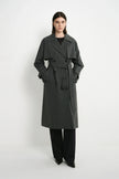 A model wearing the Rue Sophie Gavin Trench Coat in H. Charcoal with wide lapels, double-breasted buttons, a belted waist, and a relaxed tailored fit, three-quarter front view.