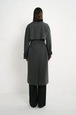 A model wearing the Rue Sophie Gavin Trench Coat in H. Charcoal with a double-breasted front, oversized lapels, belted waist, and relaxed fit, full-length front view.