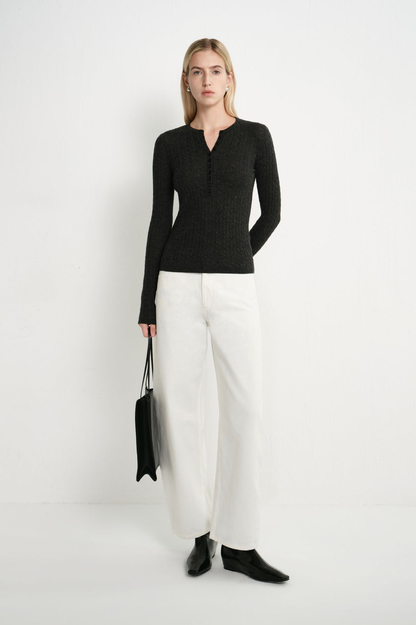 A model wearing the Rue Sophie Richie Button Up Cable Sweater in heather grey, featuring a fitted cable-knit silhouette and buttoned Henley neckline, three-quarter front view.