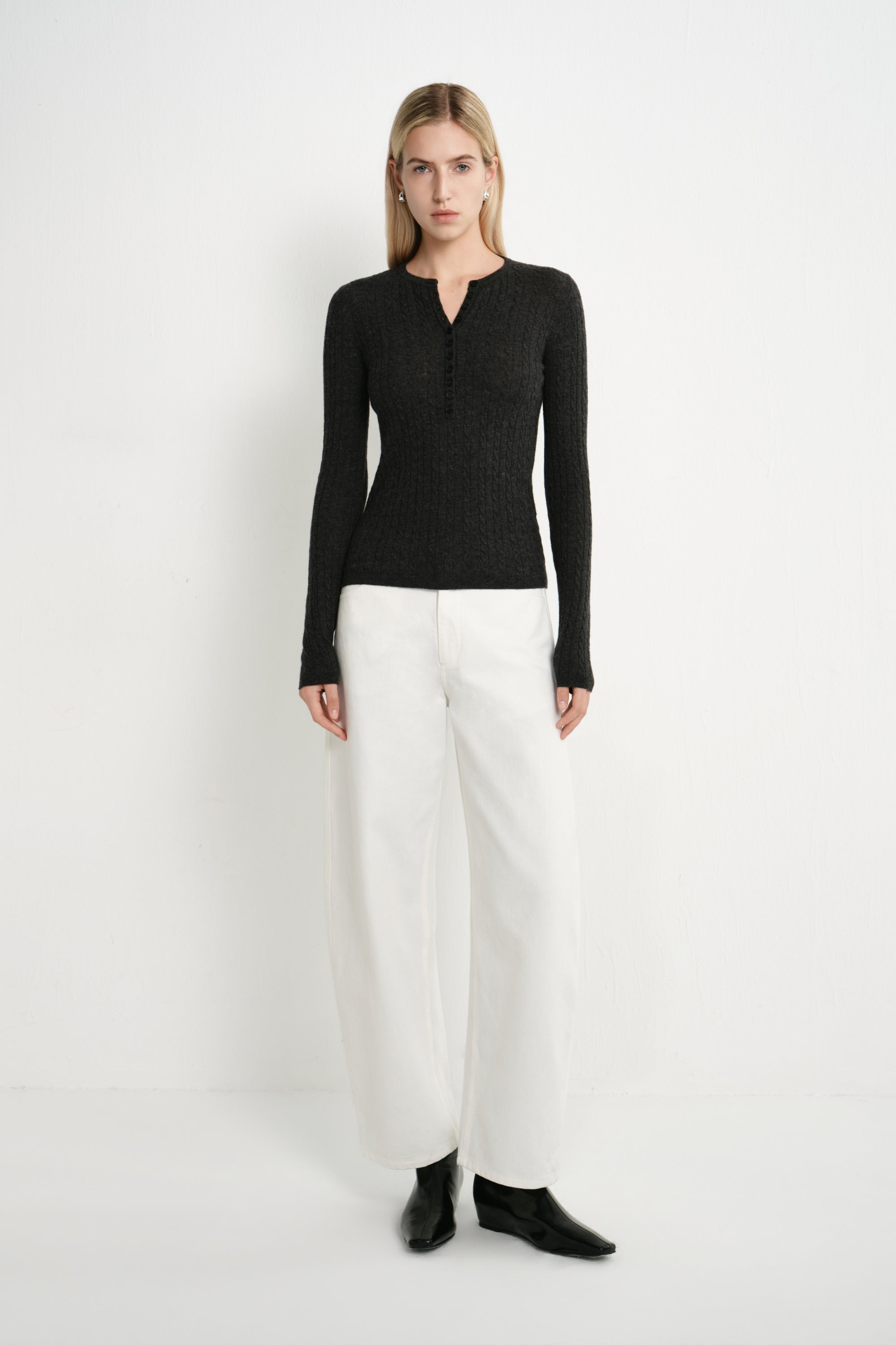 A model wearing the Rue Sophie Richie Button Up Cable Sweater in heather grey, featuring a fitted silhouette, long sleeves, cable-knit texture, and a buttoned Henley neckline, full-length front view.