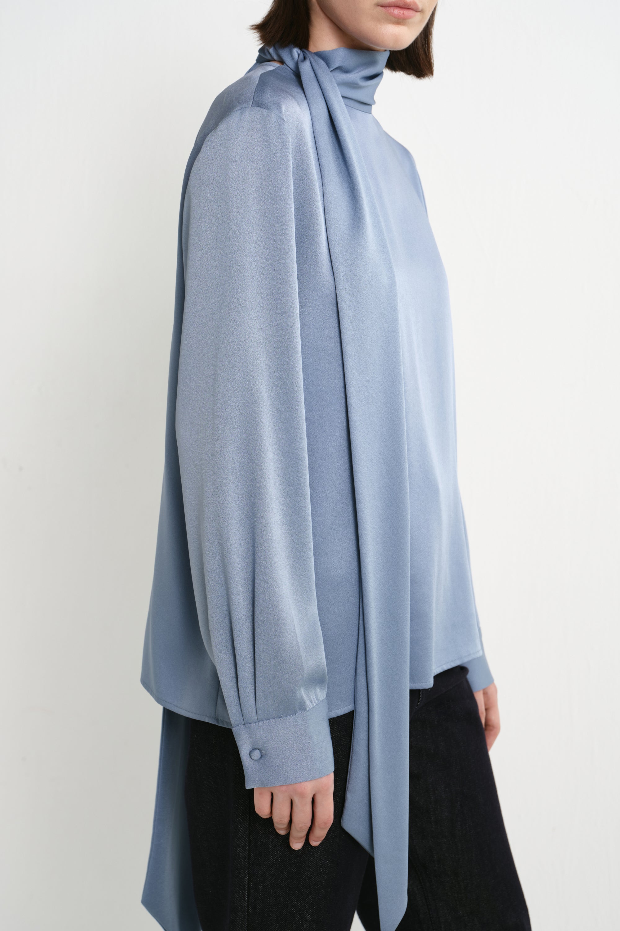Close-up of the Rue Sophie Samara Tie Neck Top in Harbour, highlighting the draped scarf neckline, long tie detail, fluid fabric finish, and buttoned cuff.