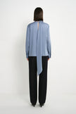 Back view of a model wearing the Rue Sophie Samara Tie Neck Top in Harbour, featuring a back keyhole opening, long scarf tie, and relaxed long-sleeve silhouette.