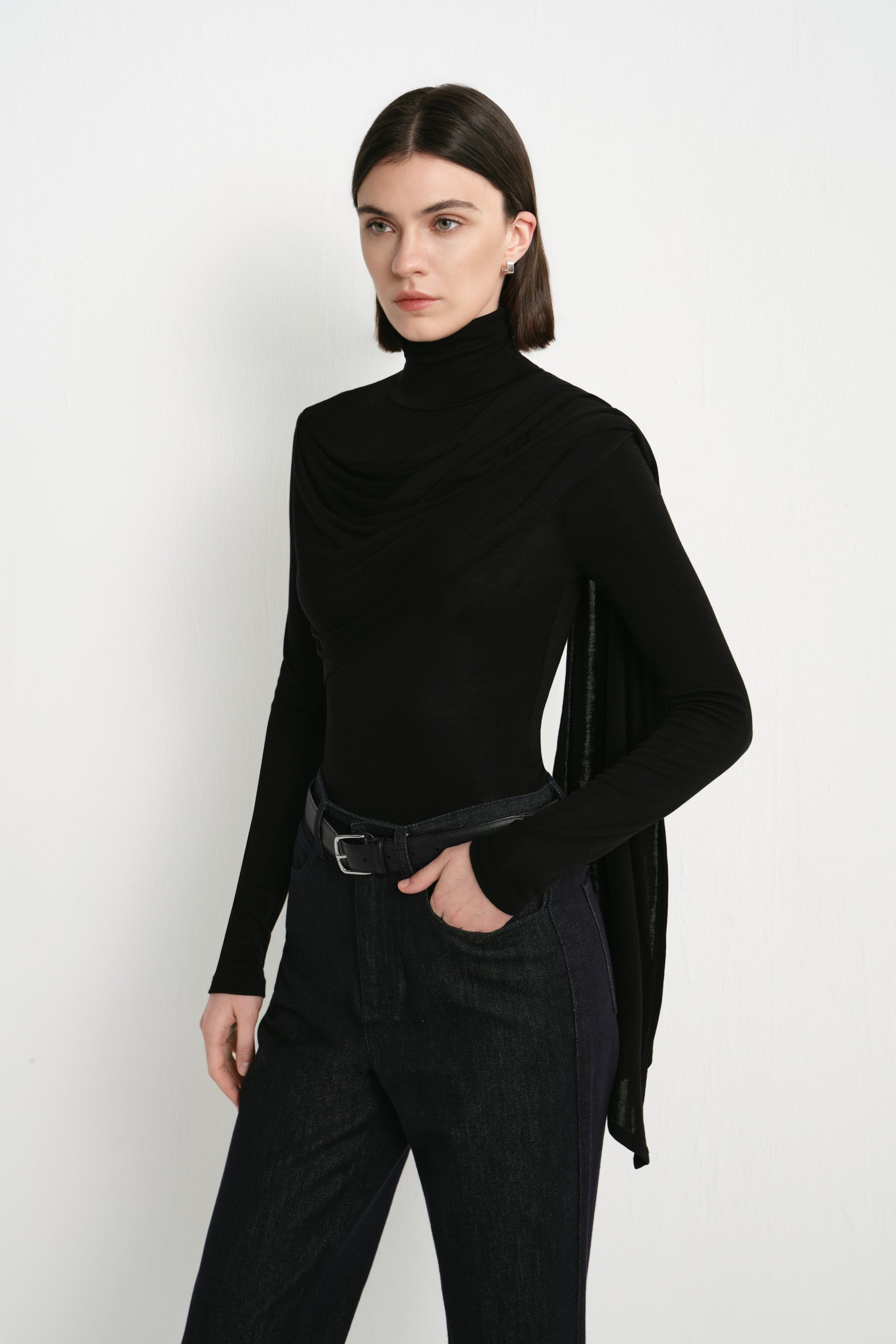 Three-quarter view of Rue Sophie’s Lila Drape Scarf Jersey Top in Black, highlighting the layered asymmetric folds and long draped scarf panel over a fitted jersey silhouette.