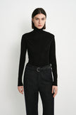 Front view of Rue Sophie’s Lila Drape Scarf Jersey Top in Black, featuring a high neckline, asymmetric draping across the chest and a close-fitting silhouette.