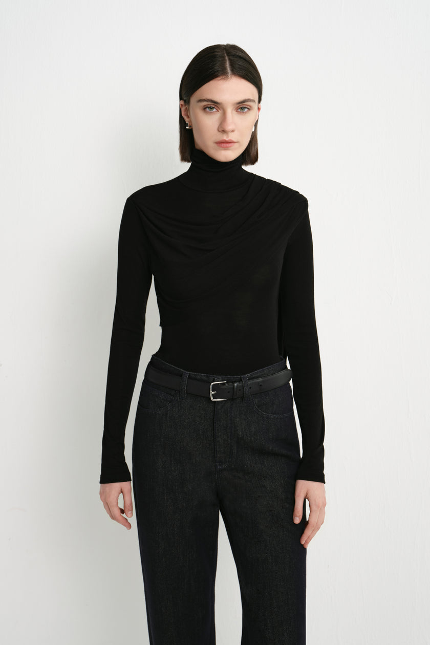 Front view of Rue Sophie’s Lila Drape Scarf Jersey Top in Black, featuring a high neckline, asymmetric draping across the chest and a close-fitting silhouette.